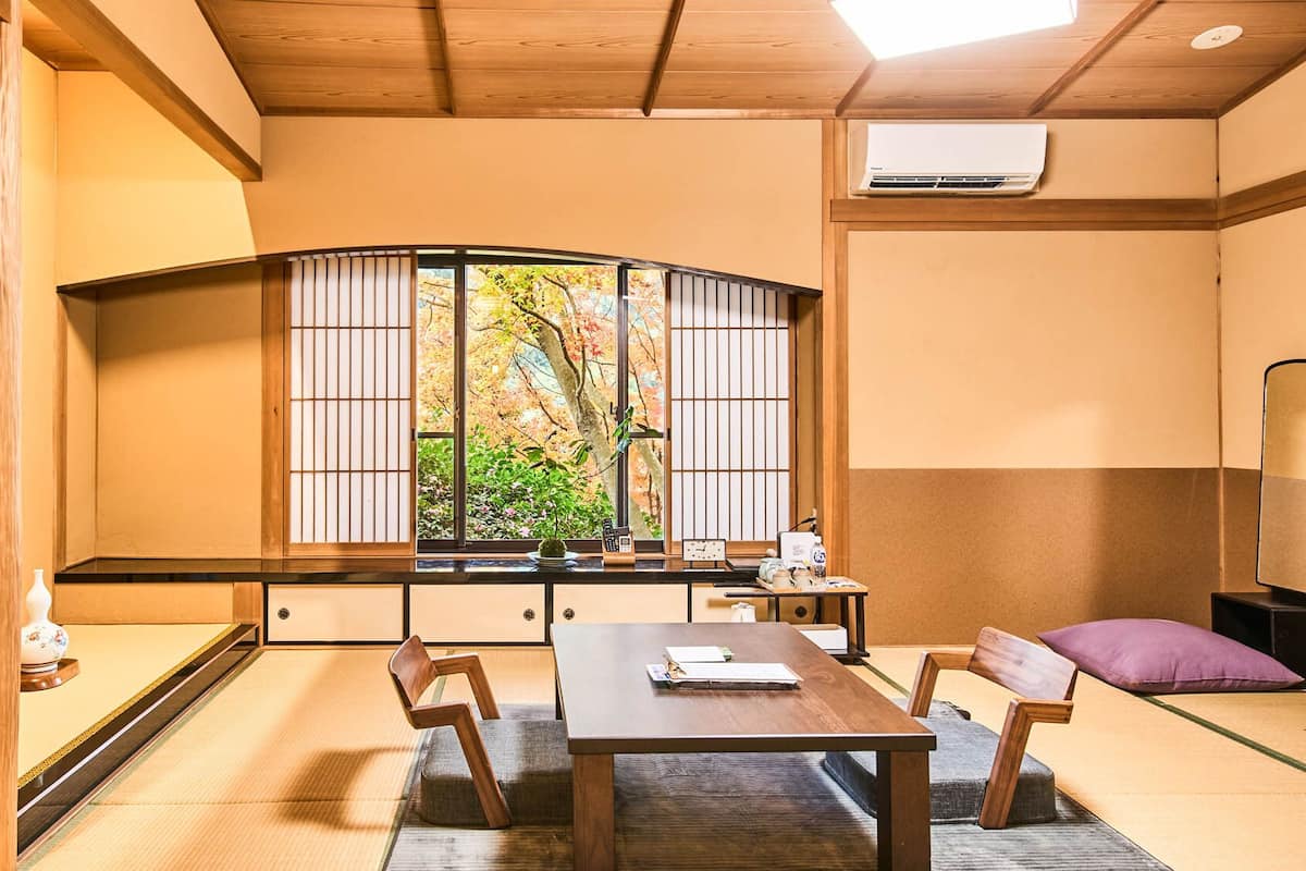 A traditional Japanese room with tatami flooring, a low table, and a shoji screen window.