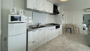 Una cocina moderna con armarios blancos, microondas integrado, estufa y pileta.