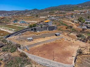 A rural landscape with a paved road, stone walls, and scattered buildings. - Finca Los Blanquitos Amazing with 3,000 m2 of land (Granadilla de Abona)