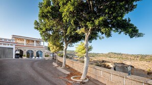 A building with a curved driveway, a stone wall, and a view of a hilly landscape. - Finca Los Blanquitos Amazing with 3,000 m2 of land (Granadilla de Abona)