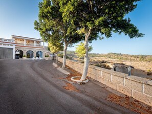A building with a curved driveway, a stone wall, and a view of a hilly landscape. - Finca Los Blanquitos Amazing with 3,000 m2 of land (Granadilla de Abona)