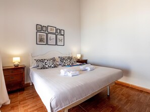 A neatly made bed with a white comforter and two pillows, a bedside table with a lamp, and a wall with framed pictures. - Finca Los Blanquitos Amazing with 3,000 m2 of land (Granadilla de Abona)