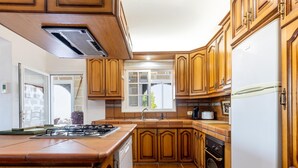 A kitchen with wooden cabinets, a stove, a sink, and a refrigerator. - Finca Los Blanquitos Amazing with 3,000 m2 of land (Granadilla de Abona)