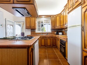 A kitchen with wooden cabinets, a stove, a sink, and a refrigerator. - Finca Los Blanquitos Amazing with 3,000 m2 of land (Granadilla de Abona)