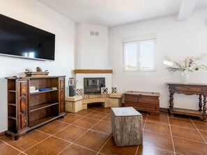 A living room with a fireplace, a television mounted on the wall, and a window with a view.
