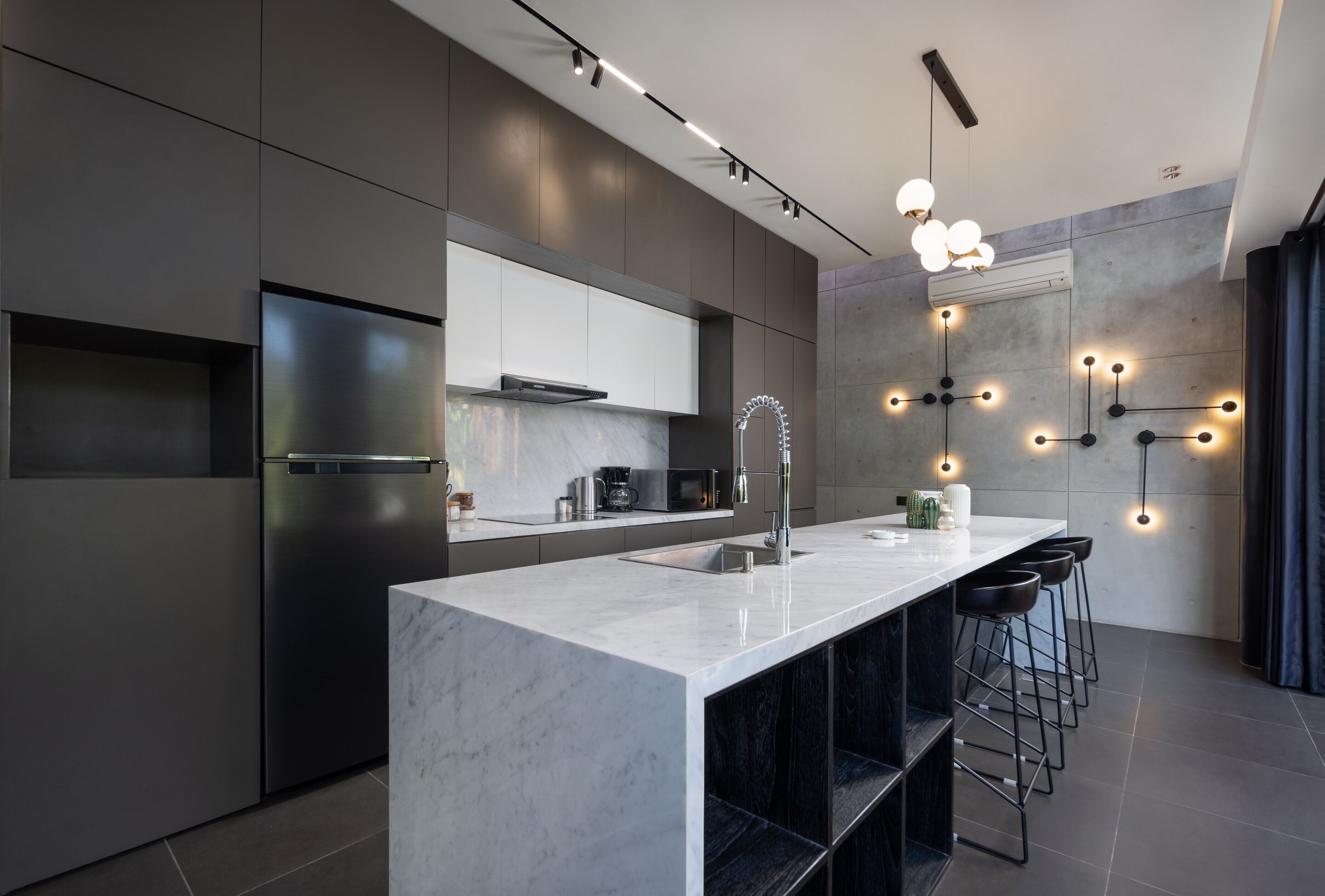 A modern kitchen with a marble island, stainless steel appliances, and bar stools.