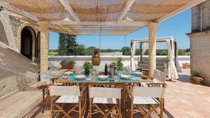 An outdoor dining area with a table set for four, surrounded by wooden chairs, under a shaded pergola. - 2040 Antica Masseria Casa Rossa - Appartamento Frantoiana by Barbarhouse (Oria)