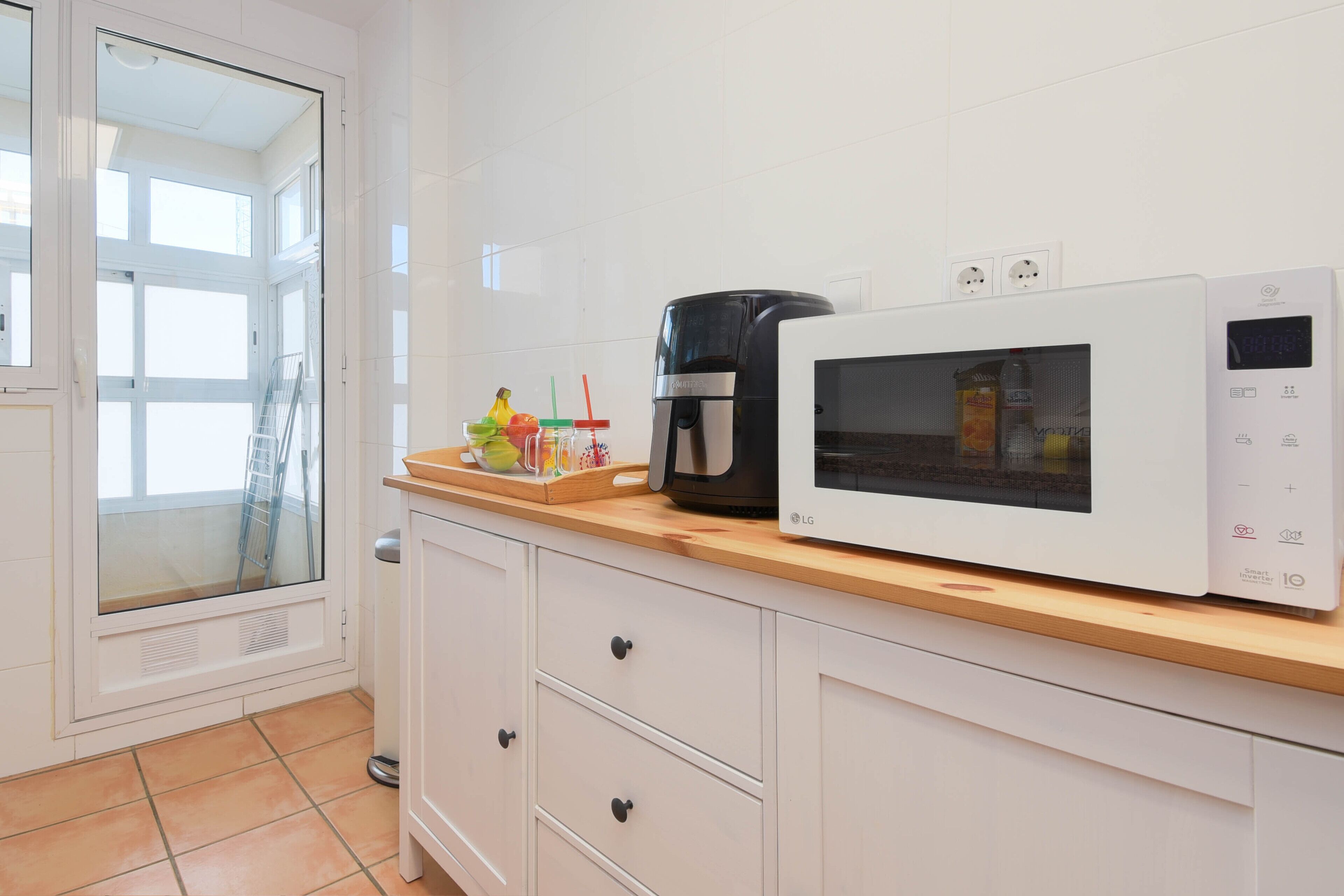 Una cocina con microondas, cafetera y ventana con vistas al exterior.