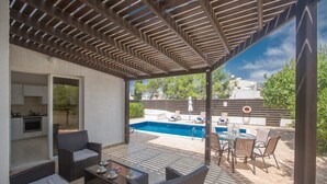Un patio couvert avec des meubles d’extérieur, une piscine et un coin cuisine.
