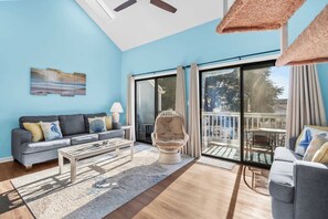 Relax in this spacious living area with a high ceiling, featuring a sofa, armchair, and coffee table.