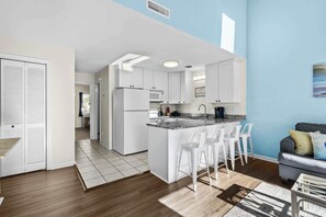 Enjoy meals in the kitchen with a central island and bar stools, adjacent to a dining area with a sofa and coffee table.