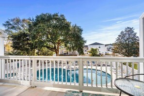 pool surrounded by a deck with a table, offering a serene outdoor space.