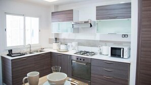 A modern kitchen with dark cabinetry, a gas stove, a microwave, and a coffee maker.