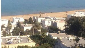 A coastal town with buildings near the beach, some with satellite dishes.