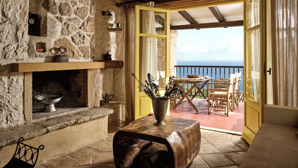 A stone fireplace with a wooden mantel, a table with a vase, and a view of the sea through an open door. - 3 Bedroom Villa with private swimming pool (Zakynthos)