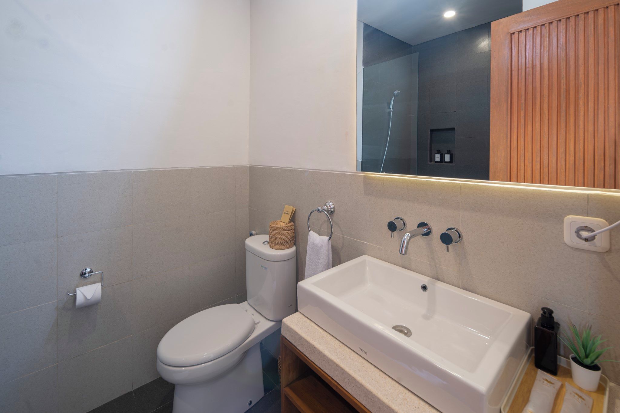 Un baño moderno con inodoro, lavabo y espejo.
