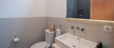 Un baño moderno con inodoro, lavabo y espejo.