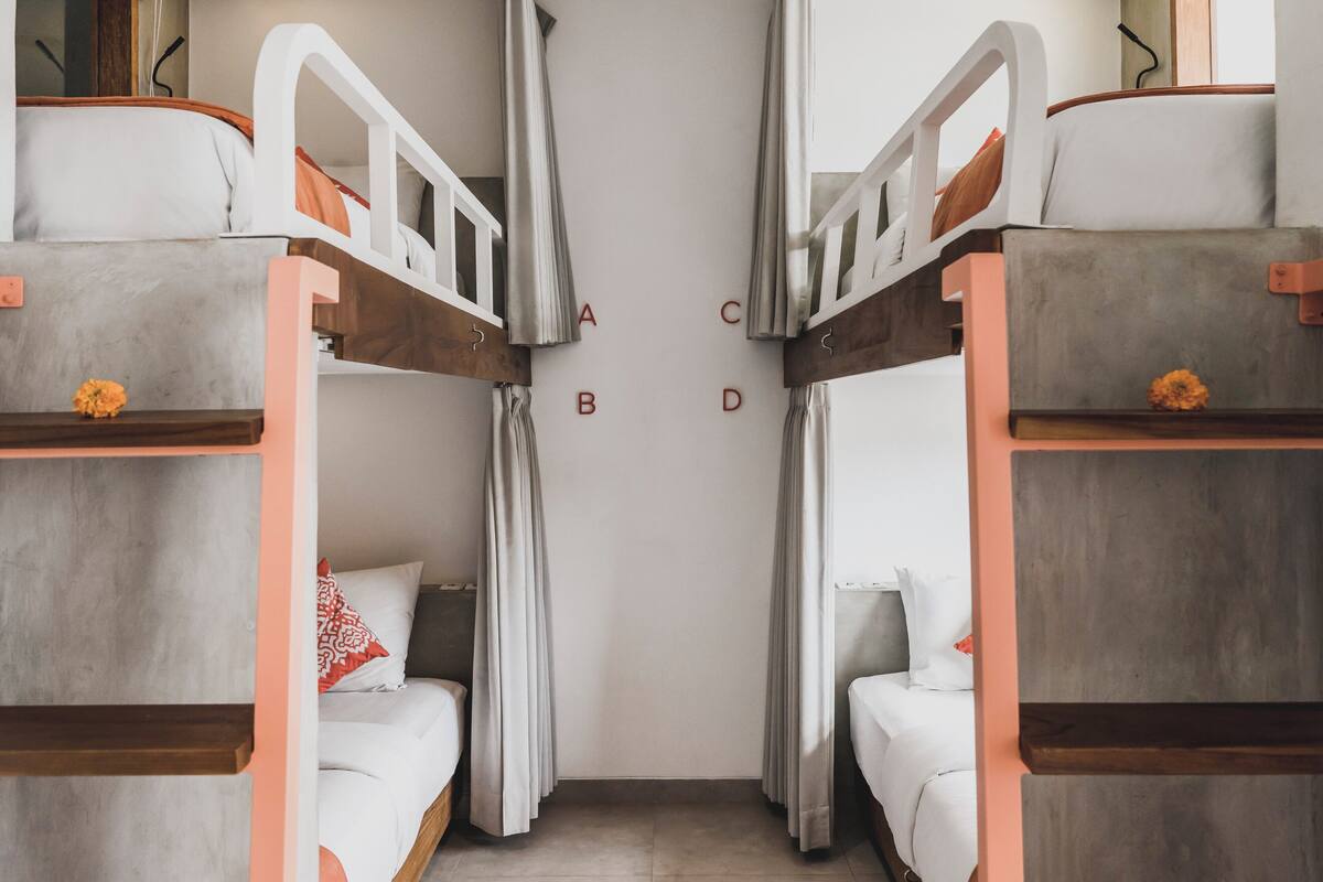 Dormitorio con literas, pared blanca y suelo de madera.