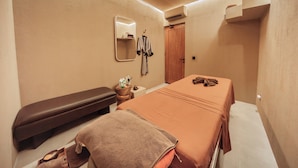 Une chambre d’hôtel comprenant un lit, une banquette, un miroir, un peignoir et une petite table avec des articles de toilette.