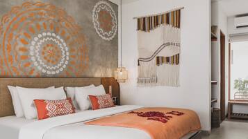 A bed with white and orange bedding, a wall with a circular design, and a macrame wall hanging.