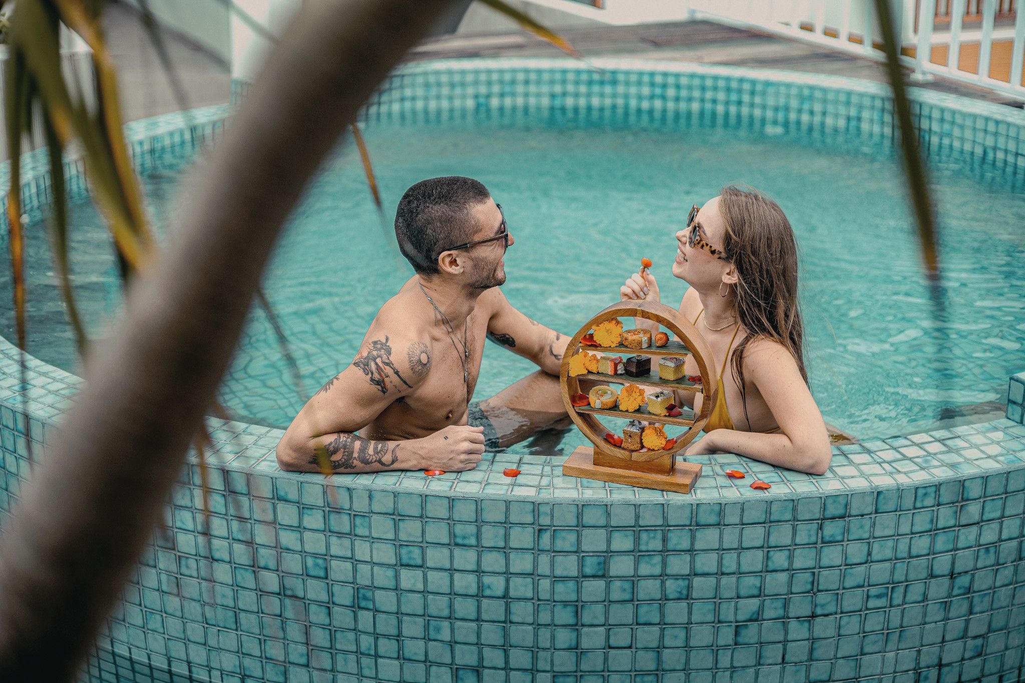 A couple in a tiled pool with a dessert stand.