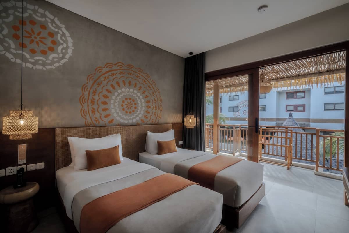 Habitación de hotel con dos camas, un ventanal grande y un balcón.