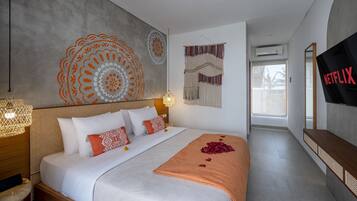 Una habitación de hotel moderna con una cama grande, un televisor montado en la pared y un ventanal amplio.
