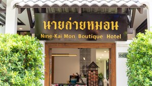 L’entrée du Nine-Kai-Mon Boutique Hotel, avec son toit recouvert de tuiles et une enseigne en thaï et en anglais.