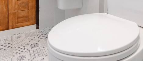 Un baño con puerta de madera, lavamanos blanco y un inodoro.
