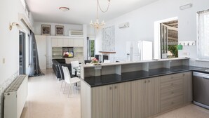 A modern kitchen with a central island, white cabinetry, and a black countertop. - Ayia Napa Holiday Villa Ch (Ayia Napa)