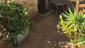 Un pequeño patio al aire libre con un muro de piedra, una mesa de madera, una silla y plantas en macetas.