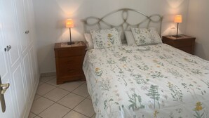 Un dormitorio con una cama, dos mesitas de noche y una puerta.