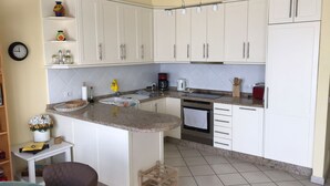 Una cocina con armarios blancos, encimera de granito, fregadero, estufa y cafetera.
