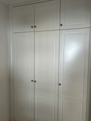 Ein weißer Kleiderschrank mit vier Türen, jede mit einer kleinen Zierdecke in der rechten unteren Ecke.