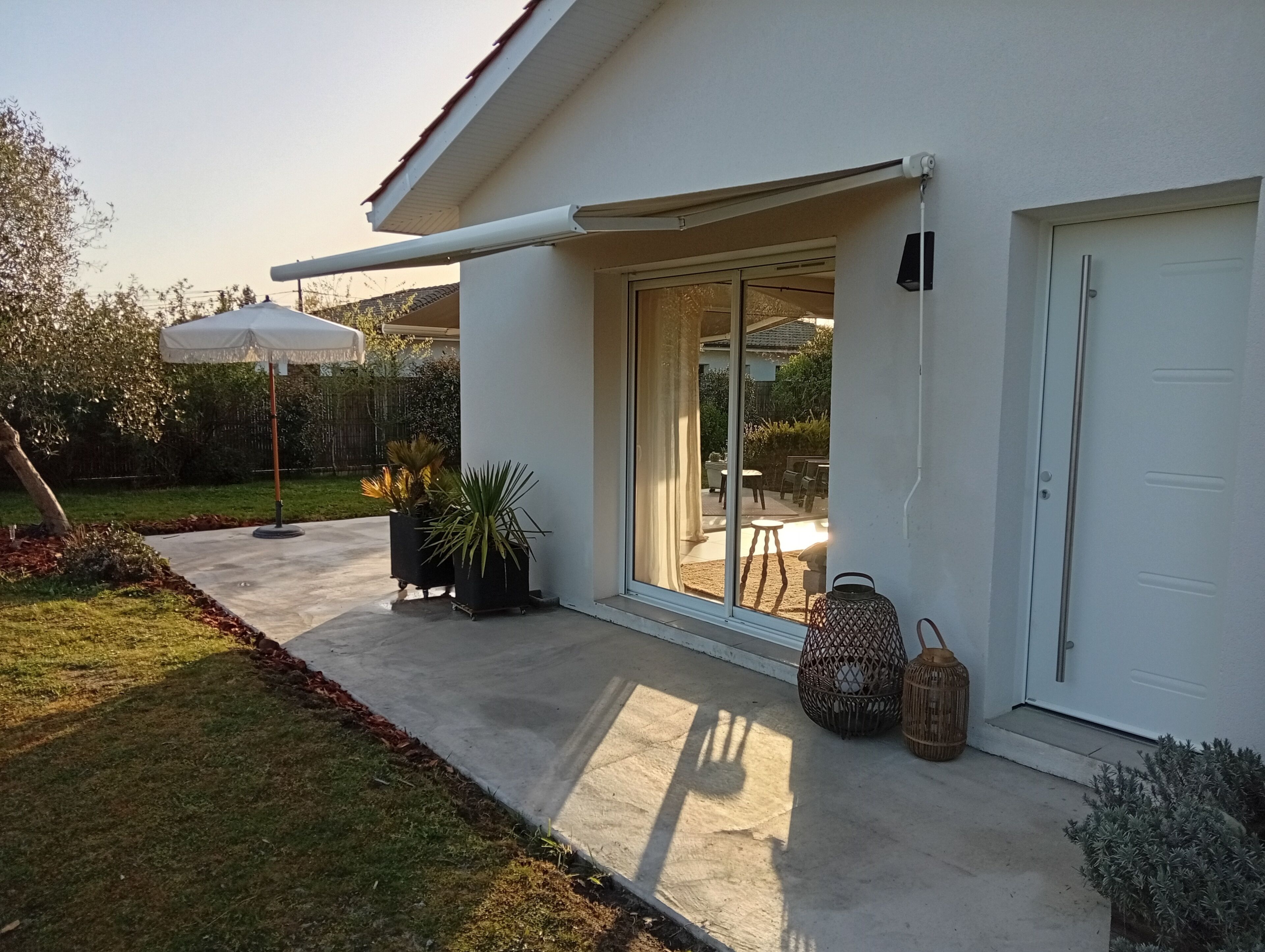 A modern house with a covered patio, sliding glass doors, and outdoor furniture.
