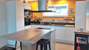 A modern kitchen with white cabinets, a central island, and a black countertop. - 3 bedroom house on the edge of a forest (Salles)