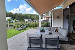 Relax in this serene outdoor space, featuring a comfortable sofa and dining area under a retractable awning.