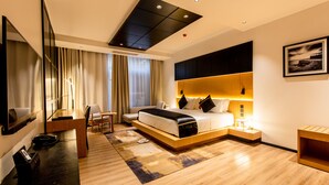 A modern hotel room with a large bed, a desk with a chair, a TV, and a large window with curtains. - Blackwood Hotel and Apartments (Dar es Salaam)