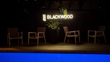 Un espace aménagé au bord de la piscine, avec une pancarte indiquant « BLACKWOOD » et deux chaises longues.