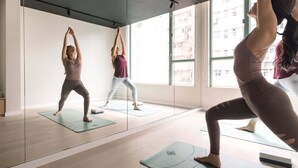 A yoga studio with mirrored walls, large windows, and yoga mats on the floor. - Weave Studios - Olympic (Kowloon)