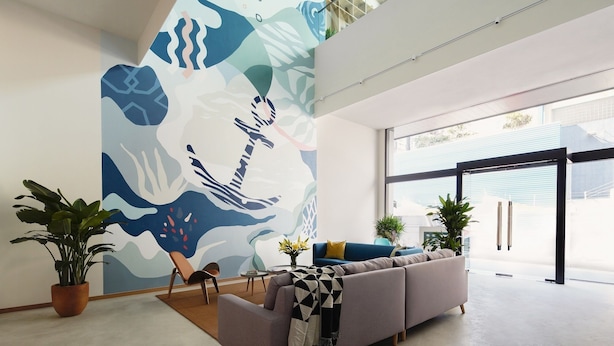A modern living room with a large abstract mural, a sofa, and potted plants. - Weave Studios - Olympic (Kowloon)