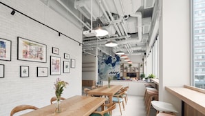 A modern interior with a long wooden table and chairs, framed artwork on the walls, and a large window providing a view of the city. - Weave Studios - Olympic (Kowloon)