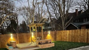 Un jardin avec une terrasse en bois, un espace détente et un chemin pavé de pierres.