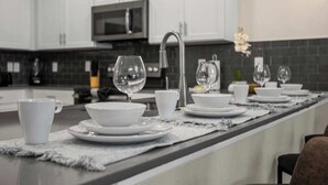 A modern kitchen with white cabinets, a stainless steel microwave, and a long countertop with a water feature.