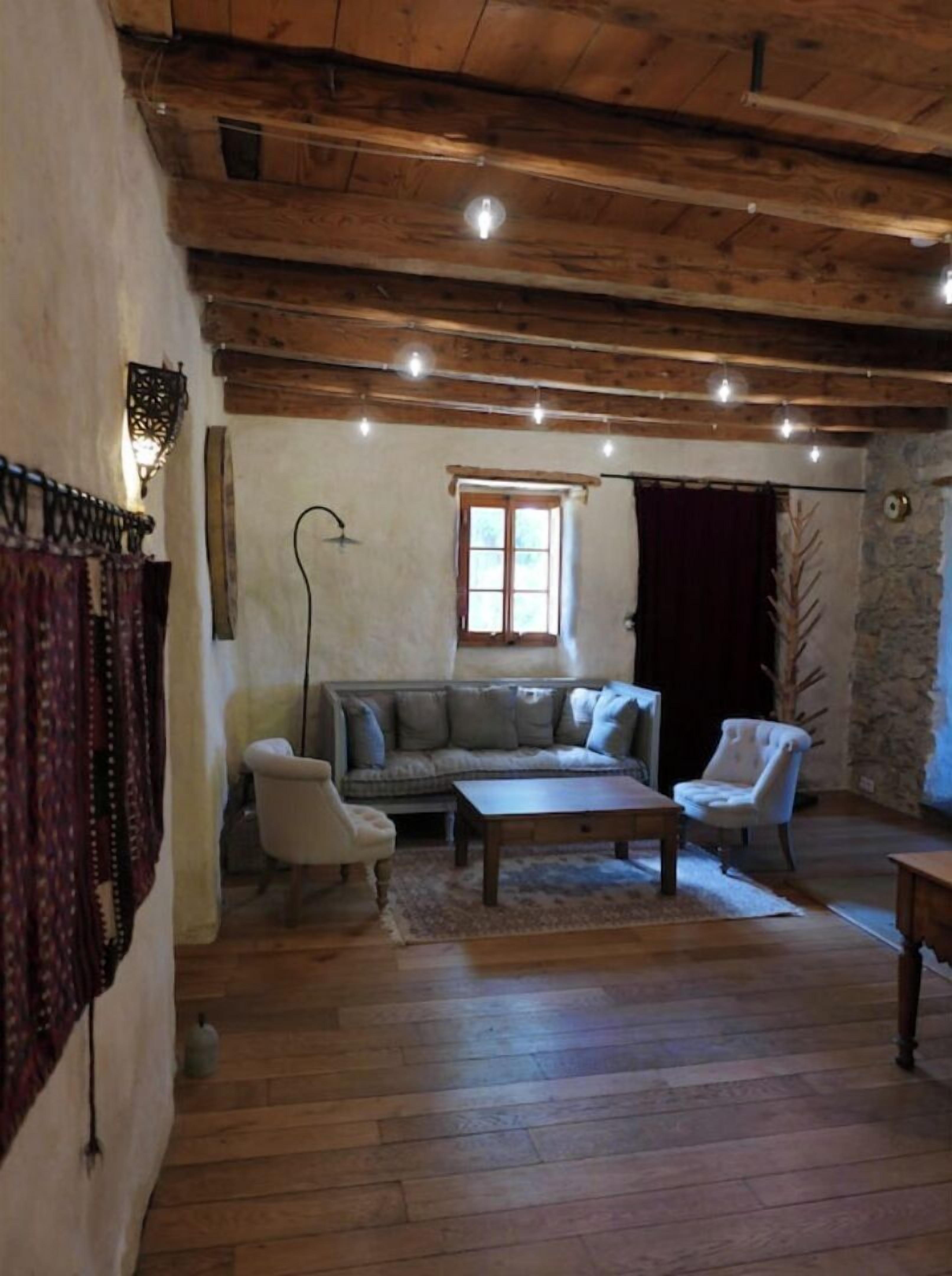 Ein rustikales Wohnzimmer mit Holzboden, Steinwand, einem Fenster und einer Couch.