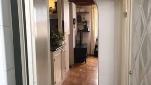 Un pasillo estrecho con suelo de madera que conduce a una cocina con armarios y una estufa.