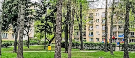 Un parque con árboles y un edificio residencial al fondo.