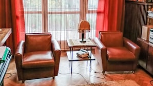 Una habitación con dos sillones de cuero, una mesita con lámpara y una estantería.