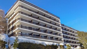 Un hotel a più piani con balconi, un muro in pietra e un paesaggio innevato.