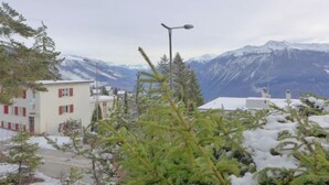 Un edificio con tetto imbiancato dalla neve, circondato da alberi carichi di neve e montagne sullo sfondo.